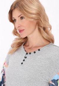 Szürke ing fekete gombokkal a nyakvonal mentén, színes mintás ujjakból készült, könnyű anyagból. Az egész textúra sima.