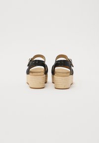 Sorte lærplattformsandaler med en espadrille-stil jute hæl, med bakre stropp og justerbar spenne. Jevn tekstur og rund form.