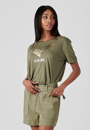 T-shirt vert olive avec un graphisme métallique et le texte "KAPORIL", associé à un short assorti et une ceinture à motifs. Tissu doux, coupe décontractée.