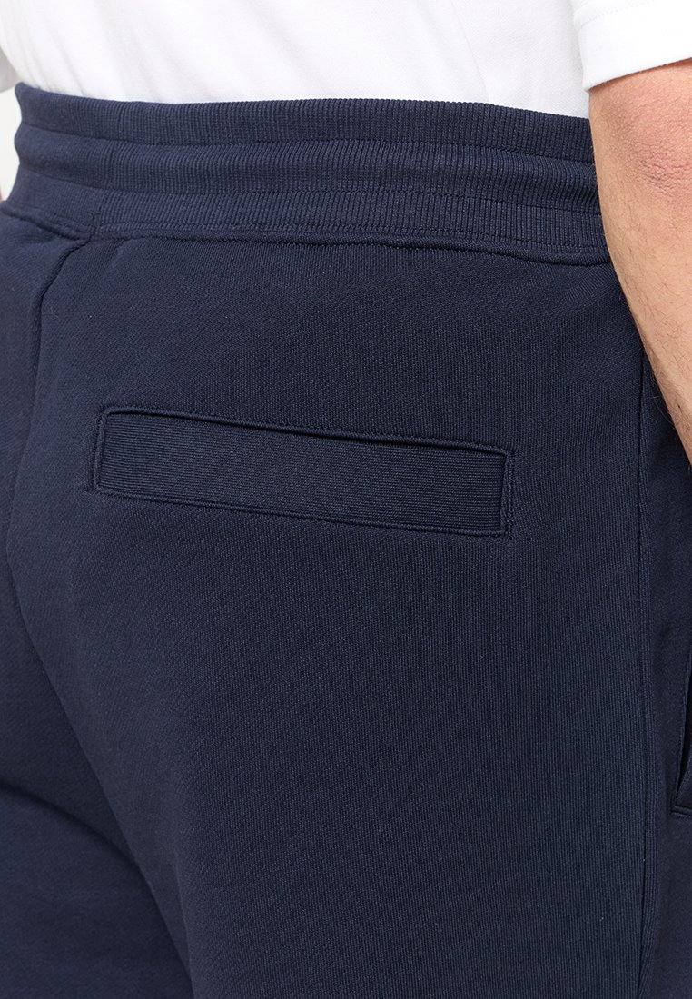 Navyblaue Sweatpants mit weichem Material, elastischem Bund und einer kleinen Gesäßtasche. Einfaches Design ohne sichtbare Muster.