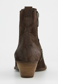 Bota de ante marrón hasta el tobillo con un tacón apilado, que presenta una cremallera lateral y detalles de costura curva en la parte trasera. Textura suave con acabado mate.