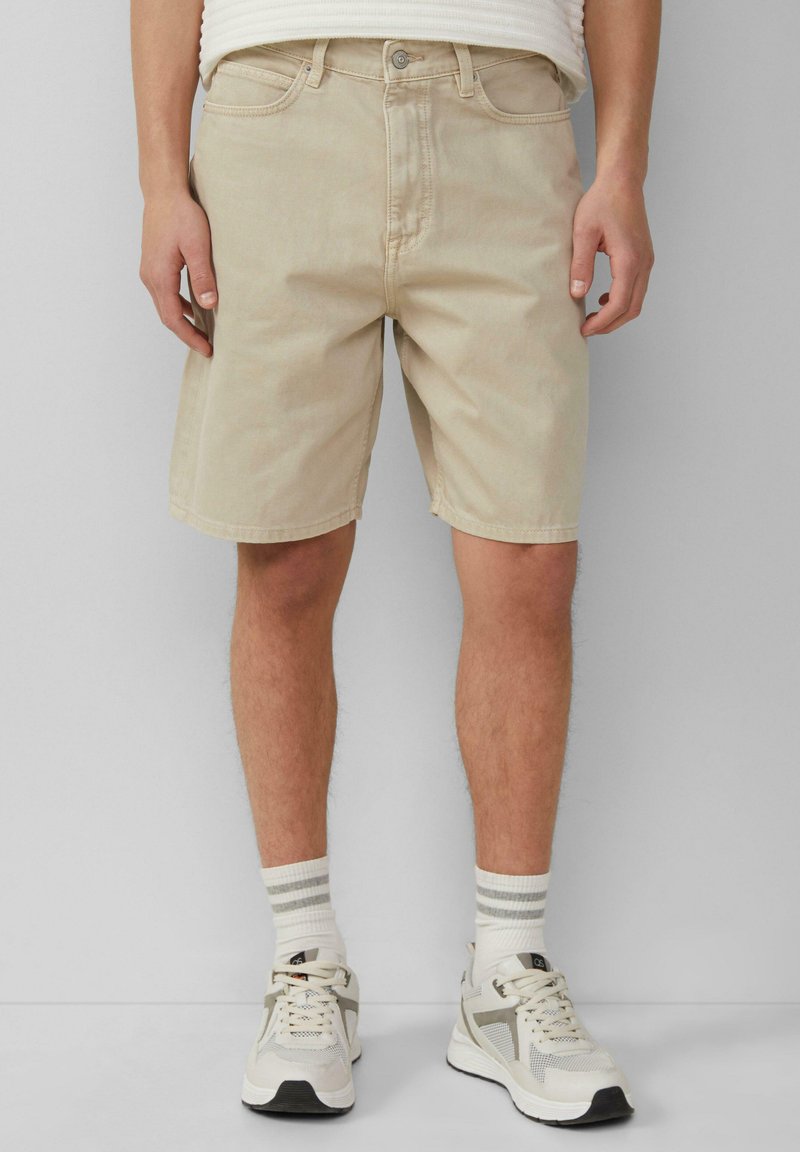 Beige denim shorts met een rechte pasvorm, voorzakken en een ritssluiting. Gecombineerd met witte sneakers en gestreepte crew-sokken.
