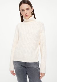 Crème coltrui met ribbelstructuur en kabelbrei ontwerp, zachte wolmix, aansluitende stijl, lange mouwen en ontspannen zoom.