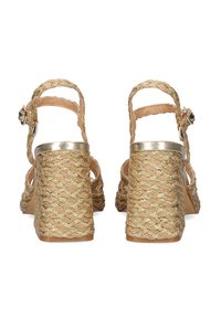 Sandalias de tacón alto con tiras, con un tacón tejido de textura dorada y tiras lisas en color beige. Presentan un acento metálico en el tacón.