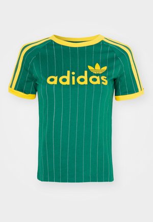Zeleni pamučni T-shirt s vertikalnim bijelim prugama, žutim detaljima i "adidas" logom u žutom fontu. Kratki rukavi i dizajn s okruglim izrezom.