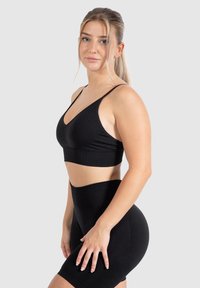 Zwarte sportbeha met verstelbare bandjes, V-hals ontwerp en bijpassende high-waisted fietsbroek, beide gemaakt van een soepele, rekbare stof.