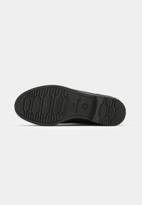 Suola di scarpa in gomma nera con grip testurizzato, caratterizzata da motivi esagonali e lineari. Marcata con il logo del brand e la taglia 37.