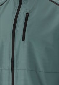 Hellgrüner Jackenabschnitt mit vertikalem schwarzen Reißverschlusstasche auf der Brust und zentralem schwarzem Reißverschlussverschluss.