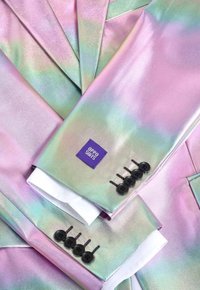 Giacca da suit iridescente con sfumature di rosa e verde, materiale lucido, quattro dettagli con bottoni neri e un'etichetta viola con la scritta "OPPO SUITS."