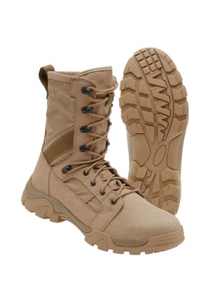 Brauner taktischer Stiefel mit schnürbarem Knöchel-Design und robuster Gummisohle, ein Stiefel steht aufrecht, der andere zeigt das Profil der Sohle.