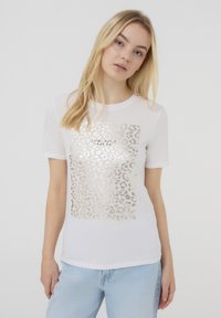 T-shirt bianco a maniche corte con un design in stampa leopardata dorata e la scritta "OGNI GIORNO È IL TUO GIORNO" al centro.