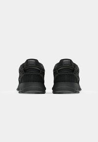 Zapatos deportivos negros con una parte superior de malla texturizada, suela acolchada y soporte amplio para el talón. Presenta un sutil logotipo en la parte trasera y los lados.