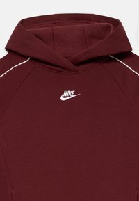 Bordo dukserica s kapuljačom od mekog materijala, s belim Nike logom i suptilnim belim detaljima duž šavova.