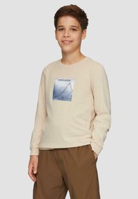 Beige Langarmshirt mit rundem Ausschnitt. Mit einem grafischen Druck von Liniendiagrammen in blauen Tönen auf der Vorderseite. Aus weichem Baumwollmaterial.