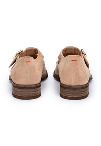 Beige Wildlederschuhe mit runder Zehenform, kurzem Absatz, goldenen Beschlägen und einem kleinen roten Akzent auf der Rückseite. Glatte Textur und lässiges Design.