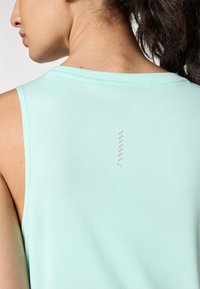 Heled sinine sporditop, millel on struktureeritud kangas, ilma varrukateta disain ja väike logo detail seljal.