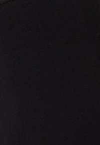 Černé legíny z měkké, elastické látky s hladkým povrchem. Mají jednoduchý, bezešvý design bez viditelných vzorů nebo zdobení.