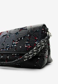 Schwarze Lederhandtasche mit floralem Ausschnittdesign, ausgestattet mit einem geflochtenen Tragegurt in Schwarz-Weiß-Akzenten und einer strukturierten Oberfläche.