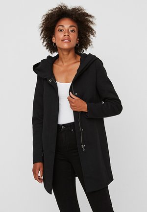 Cappotto nero con cappuccio realizzato in tessuto morbido, dotato di zip e bottoni a pressione, con una vestibilità comoda e tasche laterali.