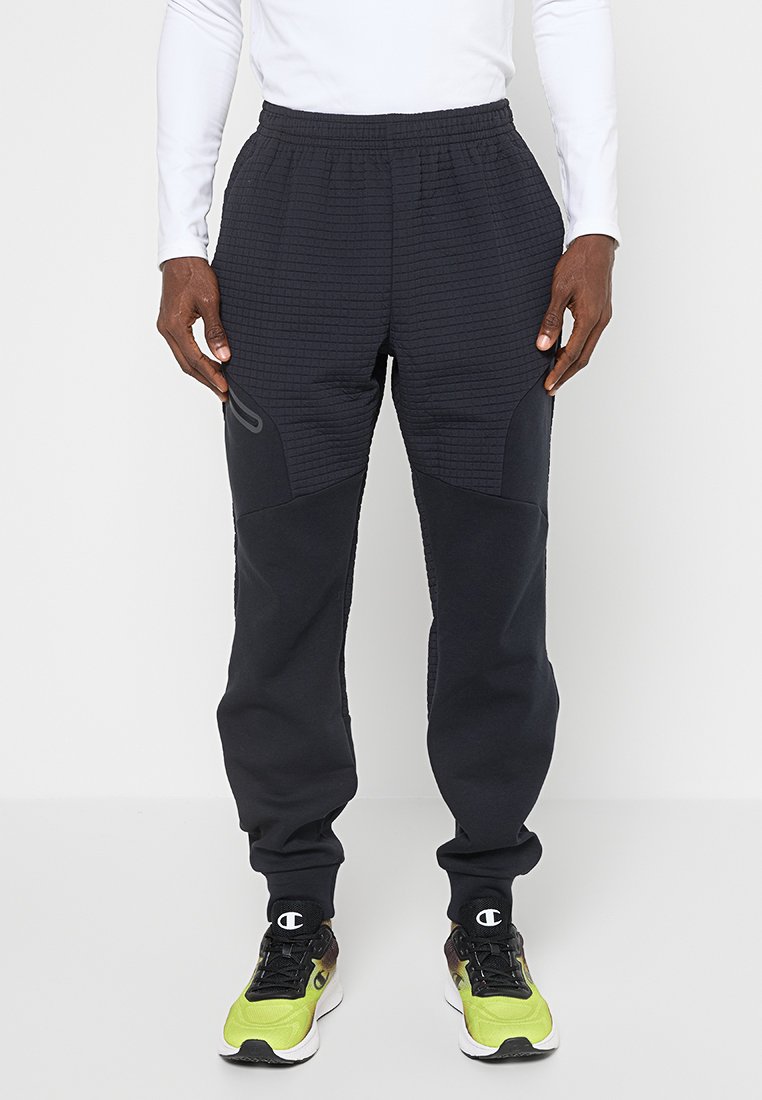 Pantalons de jogging sombres en tissu texturé avec un design côtelé. Dotés d'une taille élastique et de poignets fuselés. Soulignés par un branding subtil.