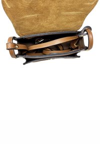 Borsa a tracolla in pelle marrone aperta che mostra il pattina in suede, una tracolla regolabile e compartimenti interni vuoti su sfondo bianco.