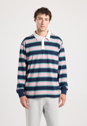 Polo-shirt à manches longues avec des rayures horizontales bleu marine, rose et verte. Il présente un col blanc et des poignets bleus. Fabriqué en matériau doux en coton.