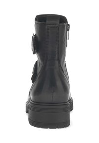 Stivaletto in pelle nera con zip laterale, dettaglio decorativo con fibbia e suola in gomma spessa con scanalature orizzontali.