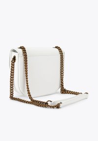 Biała skórzana torebka crossbody o zaokrąglonym kształcie, z łańcuszkiem w kolorze złotym i gładką teksturą z minimalnymi detalami szycia.