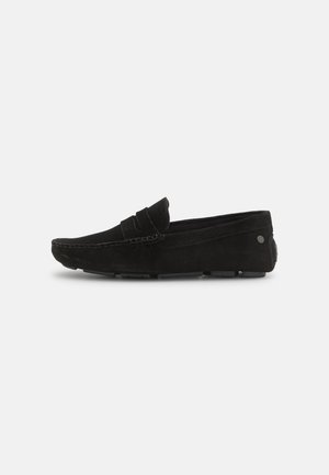 Mocassino in suede nero con design a profilo basso, dettagli cuciti e suola in gomma. Presenta una fascia nella parte superiore per una vestibilità sicura.