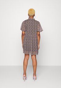 Vestido floral con mangas cortas, fondo oscuro y un colorido patrón floral. Cintura elástica, longitud por encima de la rodilla, combinado con sandalias de tacón.