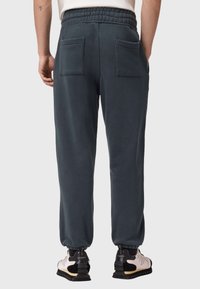 Ciemnoszare dresy z paskiem sznurkiem w talii, dwiema tylnymi kieszeniami i elastycznymi mankietami. Miękka, teksturowana tkanina; odpowiednie do noszenia na co dzień.