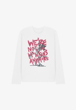 White long-sleeve shirt with a black skeleton graphic and red text reading "We're not in Hawkins anymore" across the front.