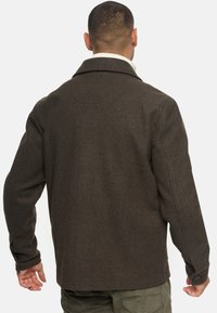Chaqueta de lana marrón con un gran cuello, puños abotonados y un acabado texturizado; mostrada desde la parte posterior, revelando un diseño simple.
