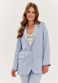 Světle modrý blazer vyrobený z hladké tkaniny, s jednobodovým zapínáním, dvěma předními kapsami a uvolněným střihem.