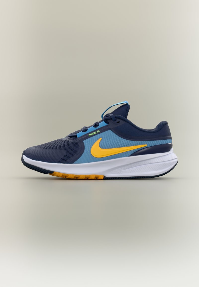 Tumesinine ja sinine Nike jooksujalats kollase Swoosh-logo, valge vahepealne tallaga ja oranžide taldade rõhutustega, külgprofiilis, millel on silt "Dynamic Fit".