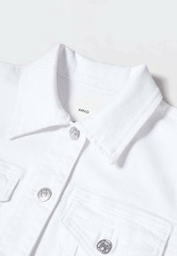 Giacca in denim bianco con colletto classico, hardware con bottoni in argento e tasche sul petto. Tessuto morbido e linee pulite. Etichetta del marchio visibile all'interno.