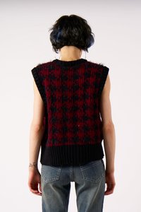 Rinnata ilma varrukatega kudum, millel on punane ja must muster, soonikkoes kaelus ja äär, pehme tekstuuriga, koos helesiniste teksadega.