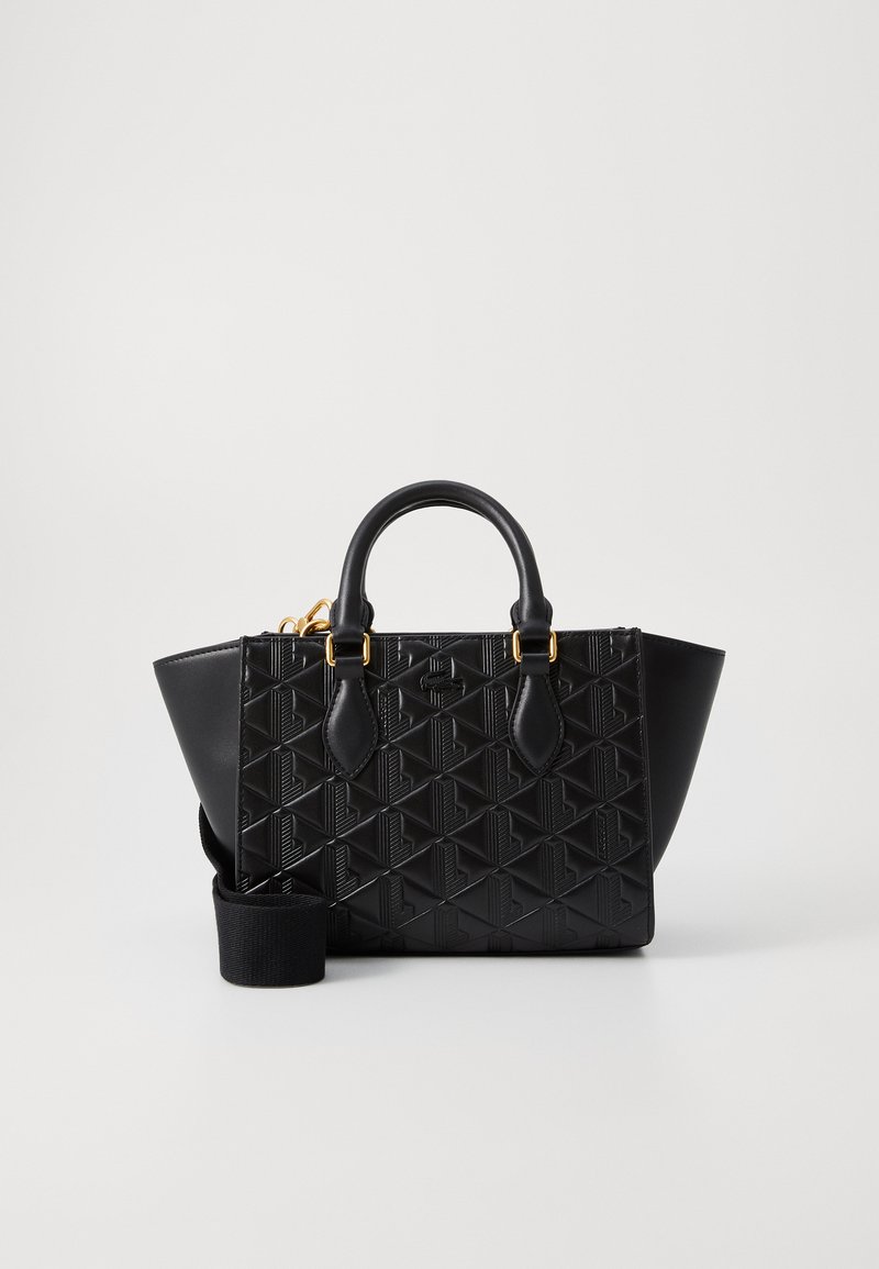Sac à main noir avec motif géométrique en relief, forme structurée, double poignées supérieures, bandoulière amovible et accents en métal doré.