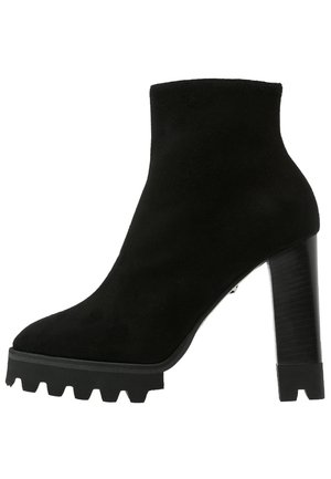 Bottine en suède noire avec talon haut épais et semelle crantée épaisse pour l'adhérence, fermeture éclair latérale.