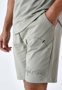 Shorts in cotone verde con logo ricamato, tasche laterali e una texture liscia. Progettati per il comfort con una vestibilità rilassata.