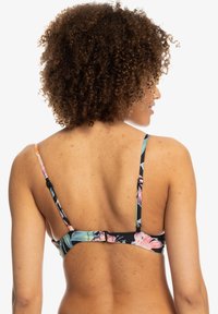 Top de bikini floral com alças ajustáveis, base preta e padrões de flores tropicais coloridas. Apresenta um fecho seguro nas costas.