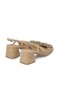 Zapatos slingback de gamuza beige con un tacón medio cuadrado. Presentan un adorno decorativo de rhinestones en el área de los dedos. Textura suave y forma estilizada.
