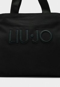 Borsa in tessuto nero con logo "LIU·JO" in rilievo. Caratterizzata da manici superiori robusti e una superficie strutturata con finitura liscia.
