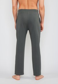 Mørkegrønne loungbukser lavet af blødt stof, med afslappet pasform, elastisk talje og sidelommer. Glat tekstur og lige ben.