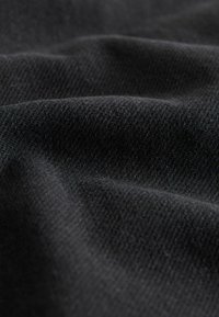 Musta tekstiili, jossa on sileä, hieman teksturoitu pinta, jossa on hienovaraisia kudontakuvioita ja vaihtelevaa kankaiden syvyyttä.