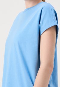 Ljusblå bomulls t-shirt med rund hals, korta ärmar och en avslappnad passform. Slät textur med minimal sömnadsdetalj.