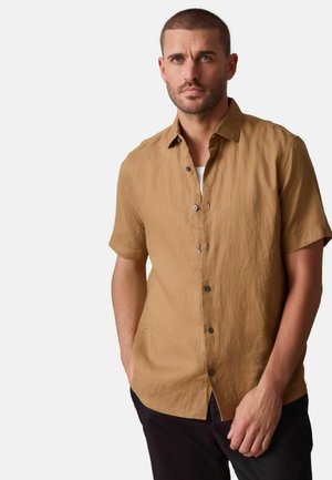 Kurzärmeliges Hemd mit Kragen aus hellbraunem Leinen, mit Knopfleiste, strukturierter Stoff und lockerer Passform, kombiniert mit dunkler Hose.