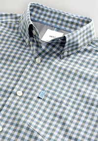 Chemise boutonnée à motif à carreaux bleu et vert olive, col boutonné, poche avant et étiquette "NEXT" à l'intérieur du col.