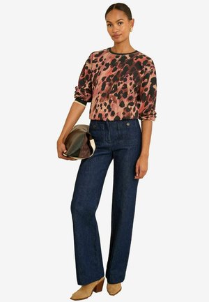 Leopardenmuster-Sweatshirt in Pink und Schwarz, dunkle blaue High-Waist-Jeans und braune Slingpumps, hält eine farbblockierte Clutch.