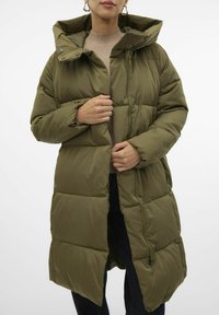 Abrigo acolchado verde oliva con capucha, que presenta un cierre frontal de cremallera, botones a presión y un diseño acolchado. Tejido texturizado y silueta larga.